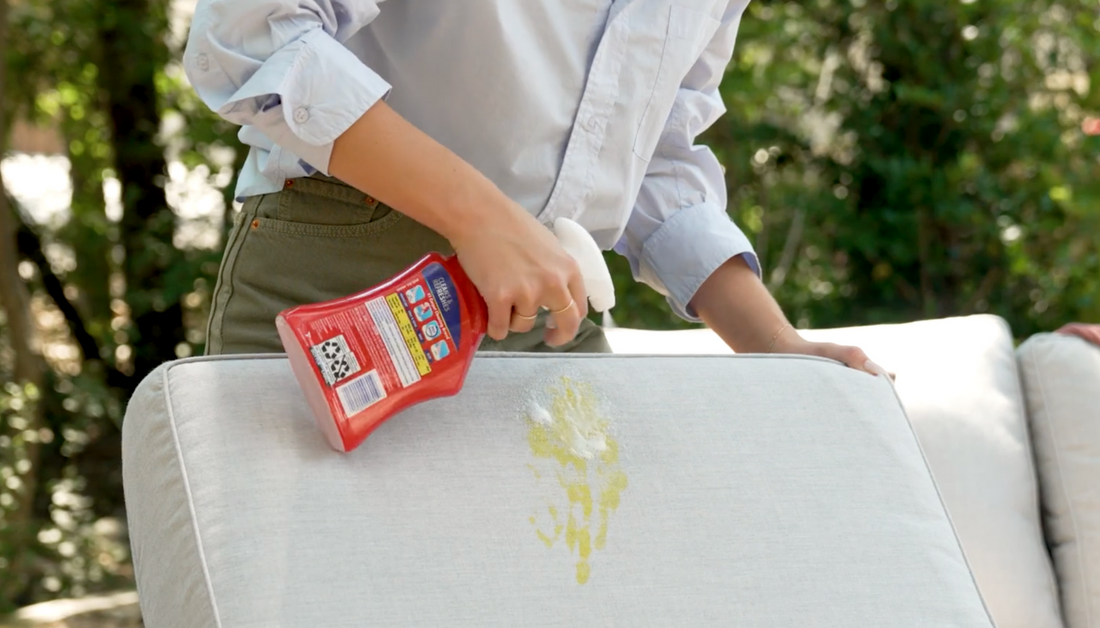 Person spraying fabric with resolve to clean it